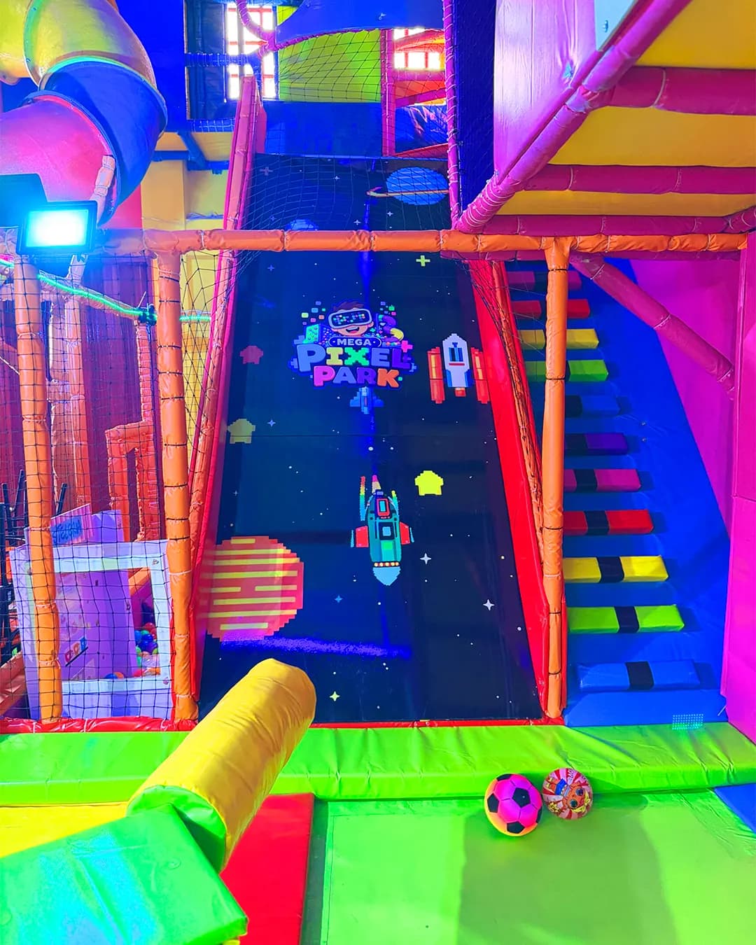Playground de Megapixel Park con escaleras de colores y el logo del parque